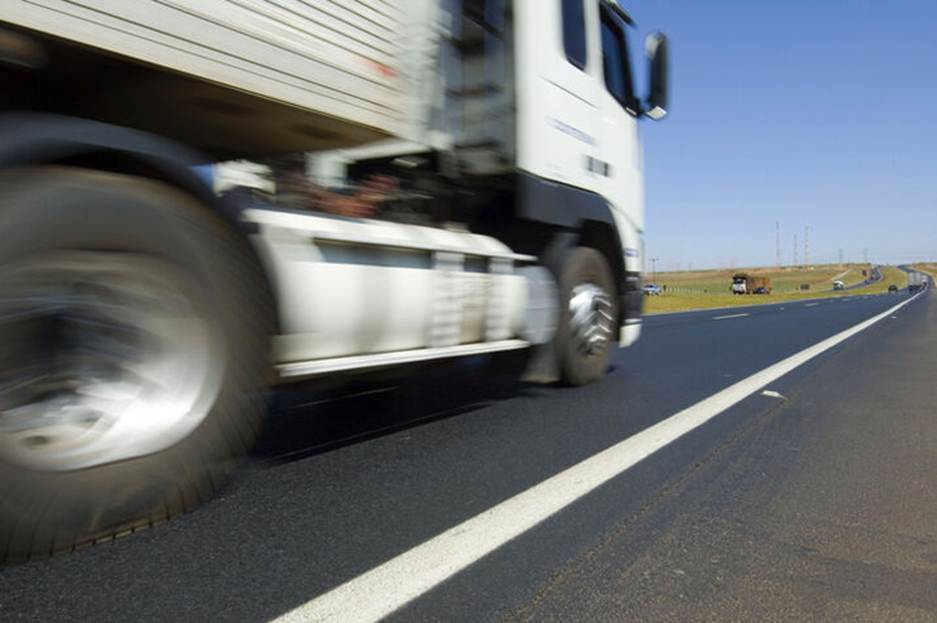 A truck drives on a clear road. The image illustrates the topic of trucking laws and truck accidents.